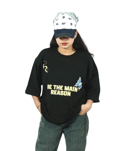 TAMRAT Black Boxy Fit T-shirt with 'Be The Main Reason' graphic and blue butterfly print worn with a cap